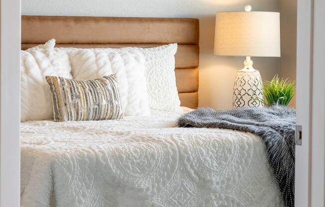 a bedroom with a bed and pillows and a lamp at Technology Park Apartments, Minnesota, 55901