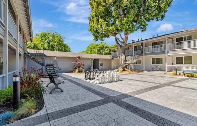 A courtyard with a bench and a tree in front of apartment buildings.