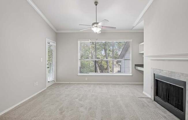 A living room with a fireplace and a ceiling fan.