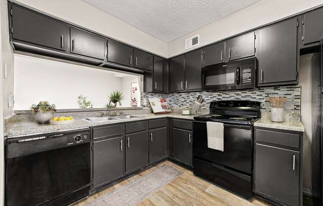 our apartments offer a modern kitchen with black cabinets and stainless steel appliances
