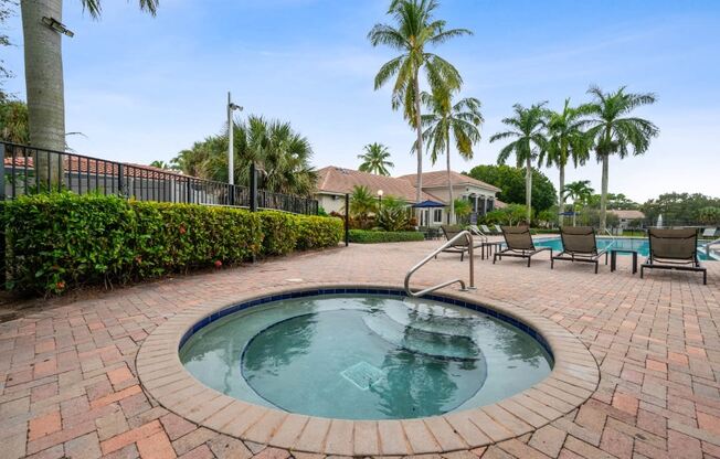 a hot tub with chairs and palm trees in a resort style pool