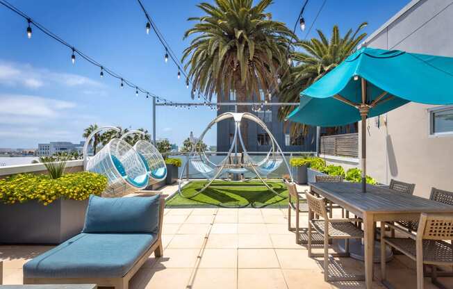 a patio with chairs and tables and a hammock in the middle of a grassy area