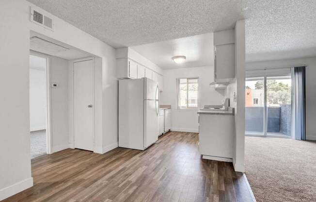 A kitchen with white appliances and wooden floors.