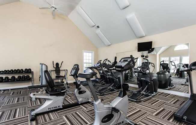 A gym with a variety of exercise equipment including treadmills, stationary bikes, and weight machines.
