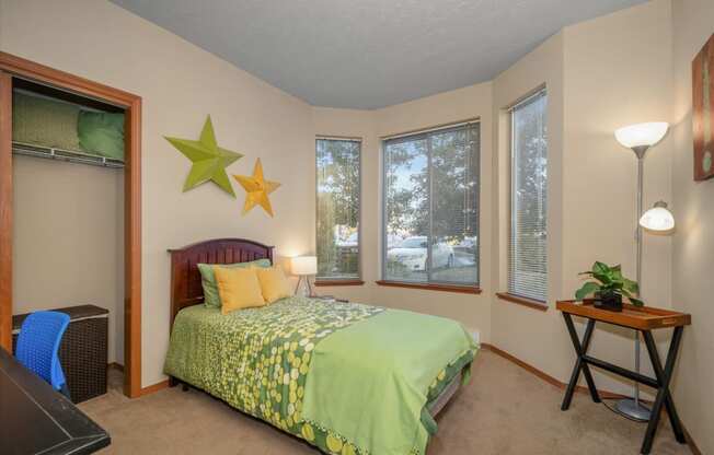 a bedroom with a green bed and three windows