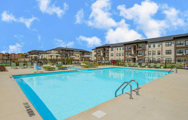 a swimming pool with an apartment building in the background