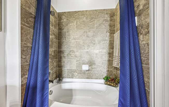 Modern bathroom with tiled bathtub at Allusion at West University apartments in Houston, TX