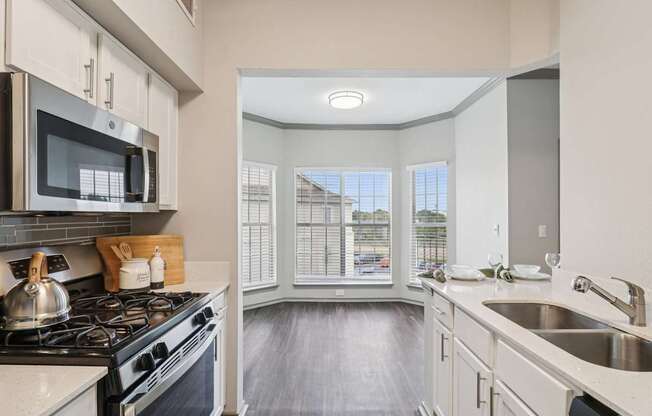 A kitchen with a stove, microwave, and sink.