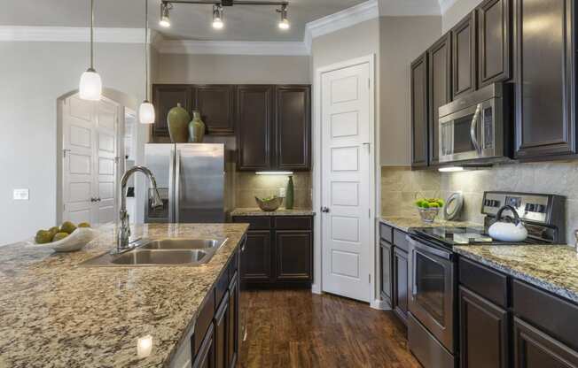 kitchen with hardwood-style flooring, brown cabinetry, and granite-style countertops with island