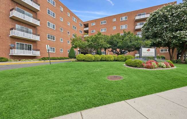 A grassy area in front of a brick building with a sign in the middle.