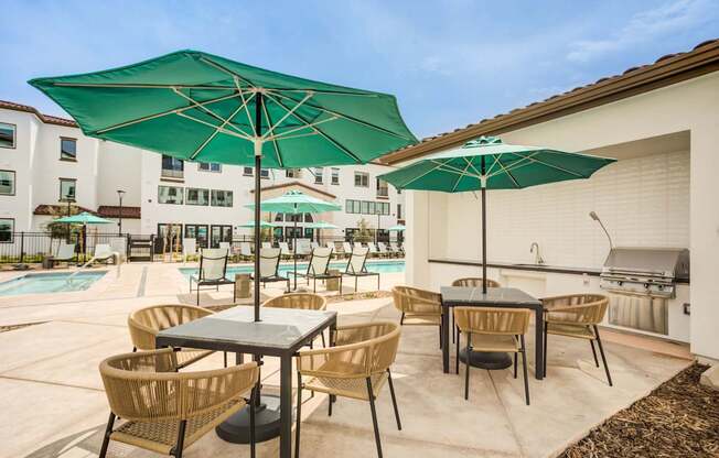 A patio with a table and chairs under a green umbrella at Pradera Apartments, California, 94582