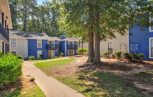 a pathway between several blue and white houses with trees