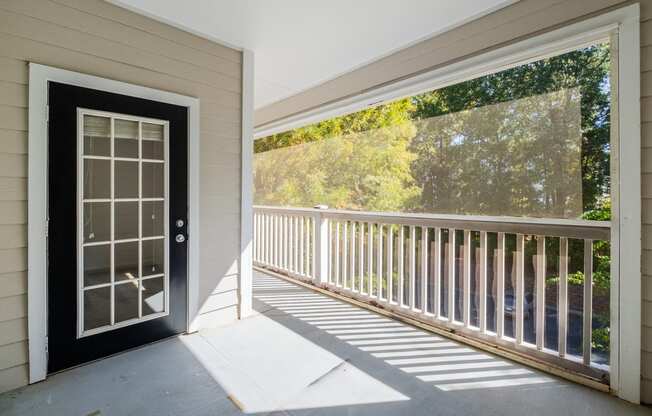 the front porch of a home with a black door and white railing