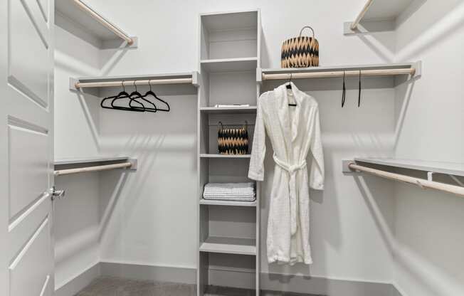 a walk in closet with a white robe and shelves