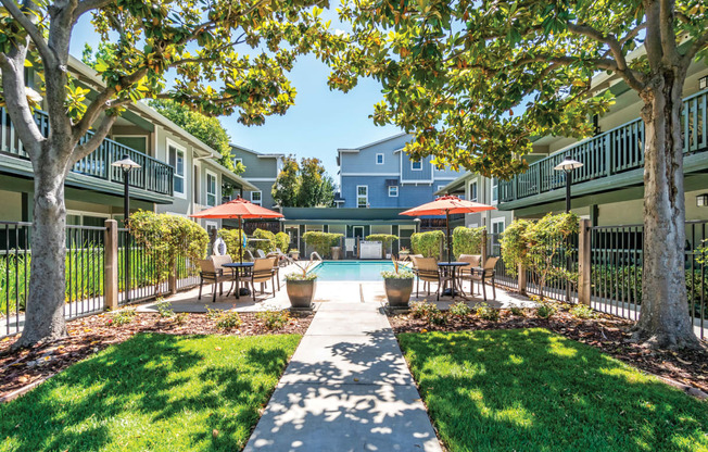 a courtyard with tables and umbrellas and a swimming pool  at Pleasanton Glen Apartments, California, 94566