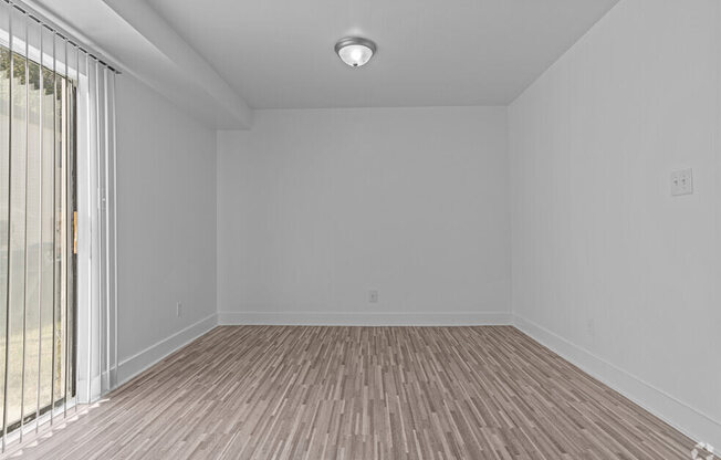 an empty living room with wood flooring and a window