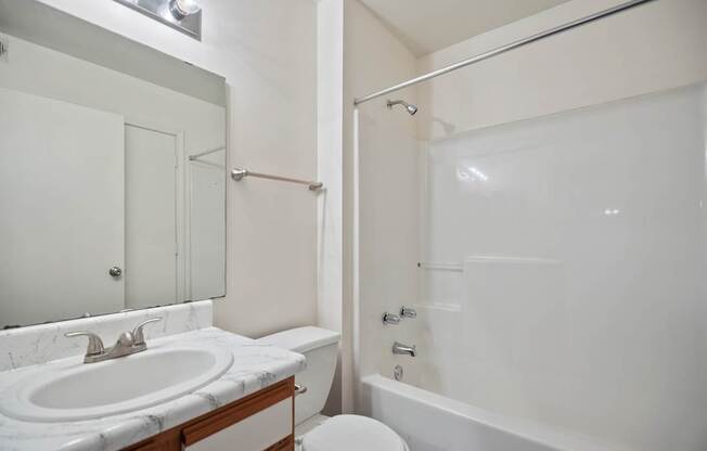 A white bathroom with a toilet, sink, and bathtub.