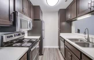 A modern kitchen with dark brown cabinets and stainless steel appliances.