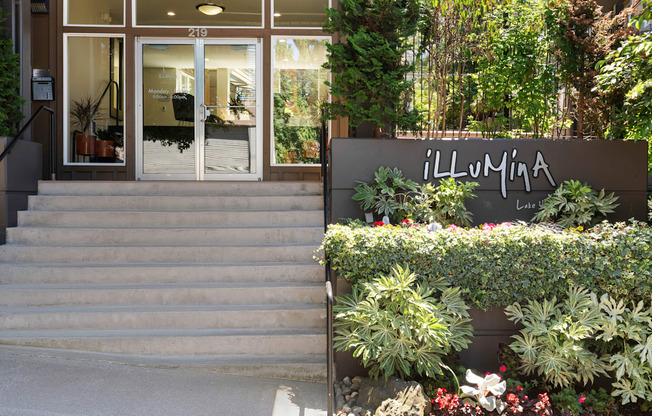 the entrance to the property building with a staircase and plants at Illumina Apartment Homes, Washington