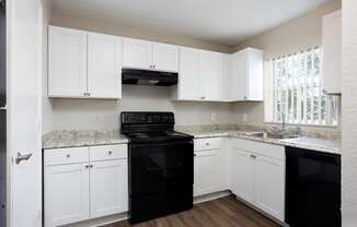 A kitchen with black appliances and white cabinets.