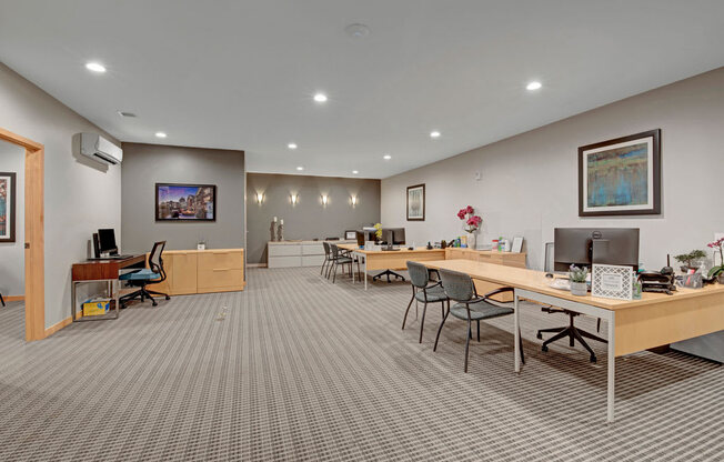 A spacious business center here at Vue at Pinnacle Park with multiple workstations, desks and chairs, computer setups, bright recessed lighting, and a quiet, professional layout for comfortable remote work and study.