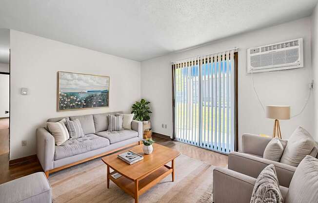 A living room with a grey couch, a wooden coffee table, and a painting on the wall.