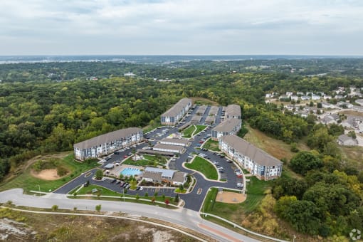 an aerial view of an apartment complex with buildings and a parking lot