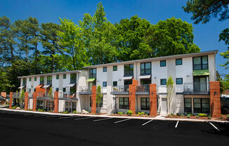 A row of modern townhouses with balconies and trees in the background.