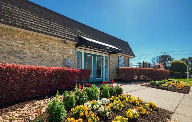 the front of a brick building with a flower garden  at Bayville Apartments, Virginia, 23455