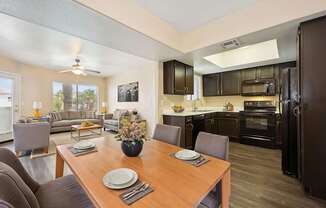 A modern kitchen with dark brown cabinets and a wooden dining table set for two.