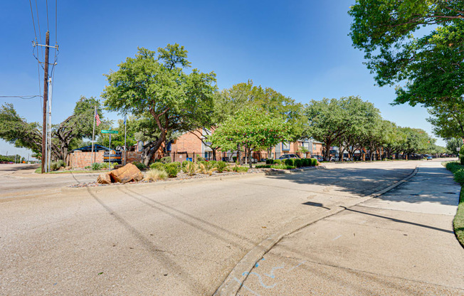 an empty street with houses and trees on the side of the road