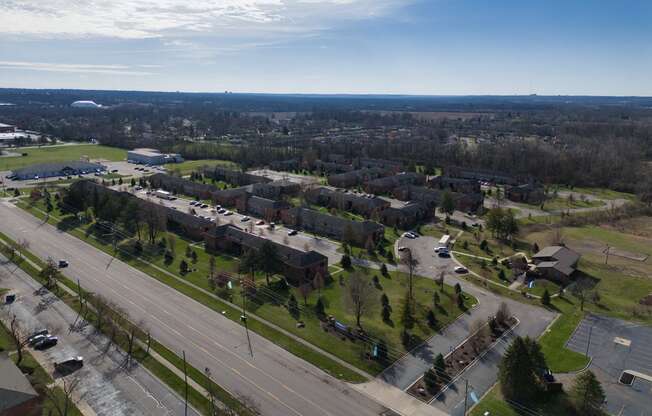 an aerial view of a neighborhood with an empty street and cars on a highway