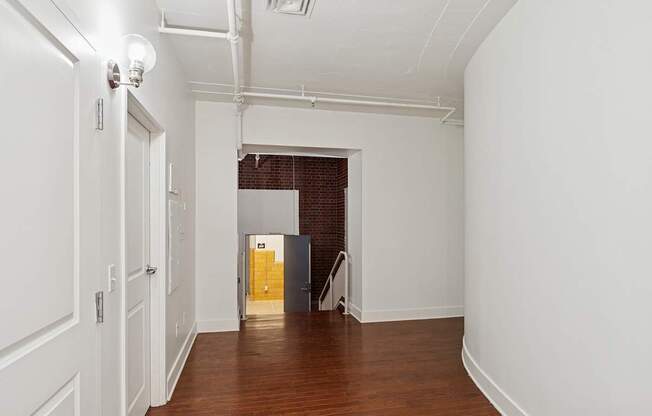 A long white hallway with a door at the end.
