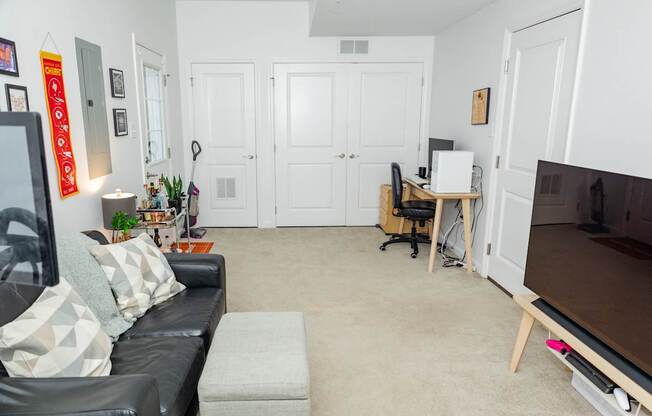 A living room with a black couch and a television.