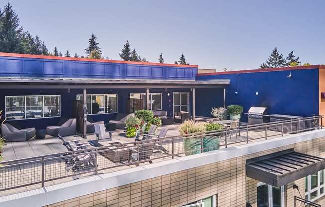 a rooftop patio with furniture and a blue building with a red roof