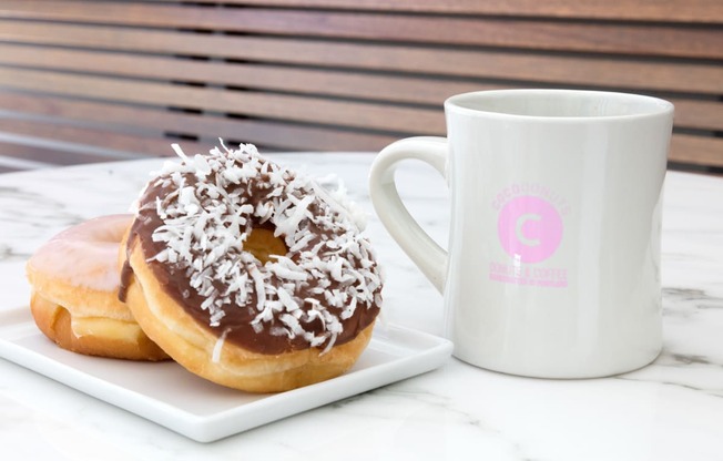 two donuts on a plate next to a coffee mug