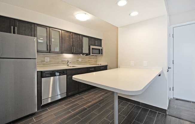 a kitchen with a white counter top and a stainless steel refrigerator
