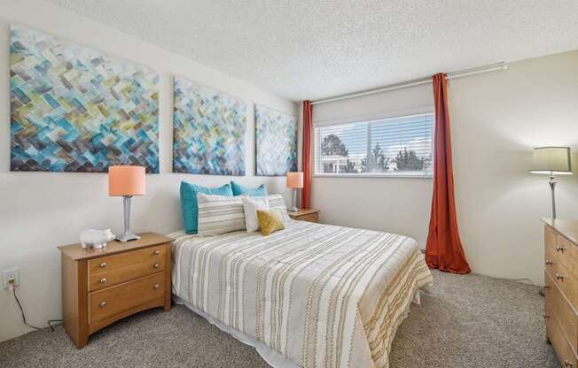 A bedroom with a bed, nightstand, and two wall art pieces.