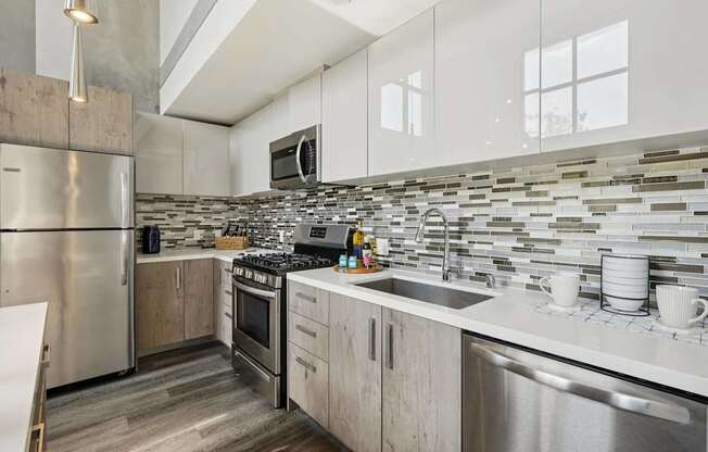 A modern kitchen with a stainless steel refrigerator and a tiled backsplash. at The Mansfield at Miracle Mile, Los Angeles
