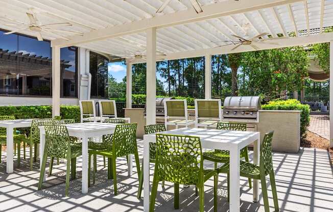 A white table and green chairs are set up under a white canopy.