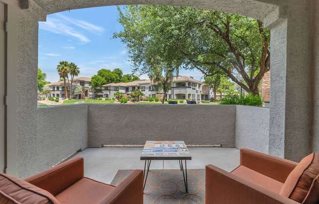 a patio with couches and a table in front of a tree