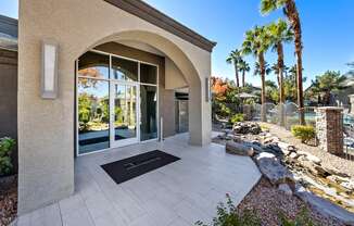 A modern house entrance with a stone wall and a black doormat.