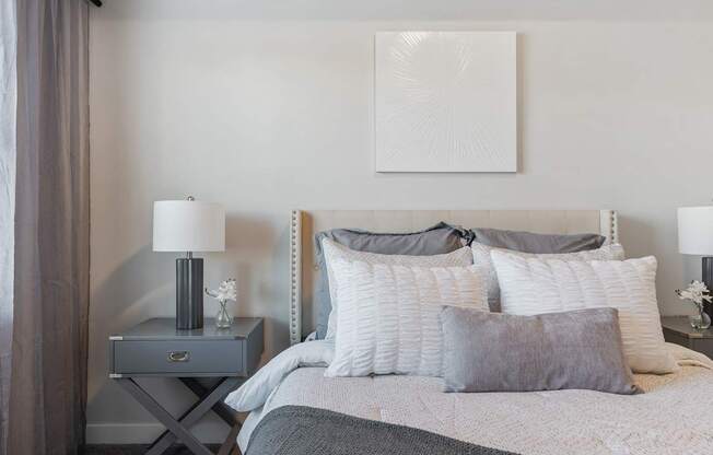 a bedroom with a bed and pillows and a nightstand with a lamp and