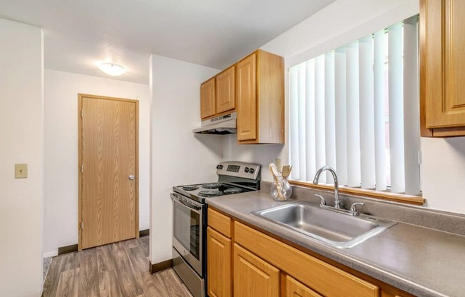 A kitchen with wooden cabinets and a stainless steel sink.at Alder Creek Apartments, Vancouver, WA