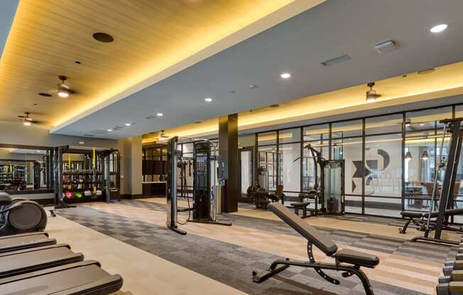 a gym with treadmills and weights in a building with glass walls at Aura Stonebridge, Richmond, VA