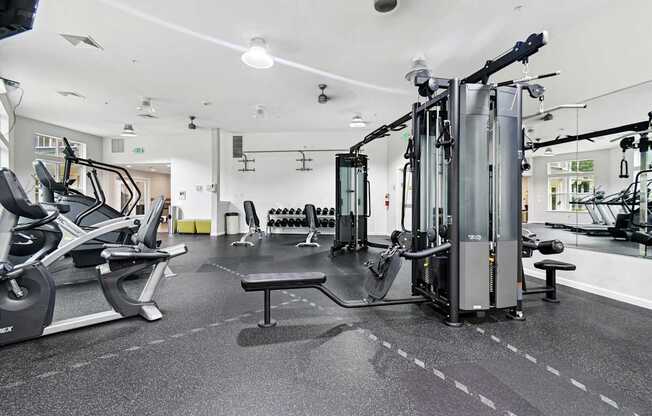 A gym with a variety of equipment including treadmills, weights, and exercise machines.