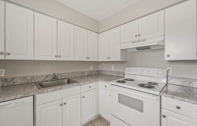 A kitchen with white cabinets and a white stove top oven.