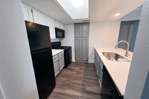 a kitchen with white cabinets and black appliances