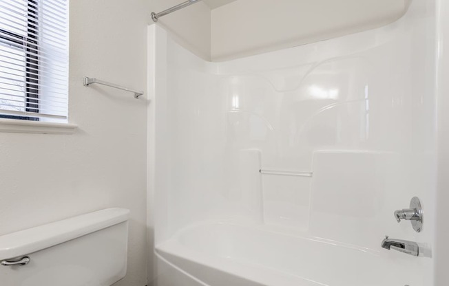 A white bathroom with a tub, shower, and toilet.