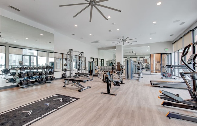 a spacious fitness center with weights and cardio equipment and large windows